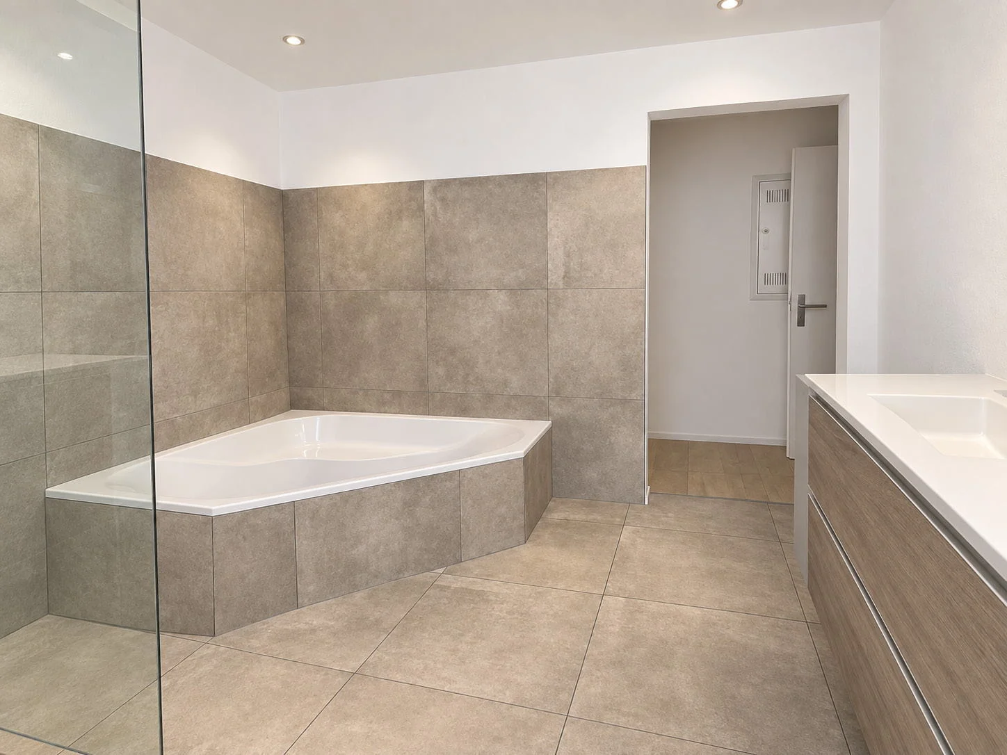 Badezimmer mit Eckbadewanne und grossformatigen Keramikplatten